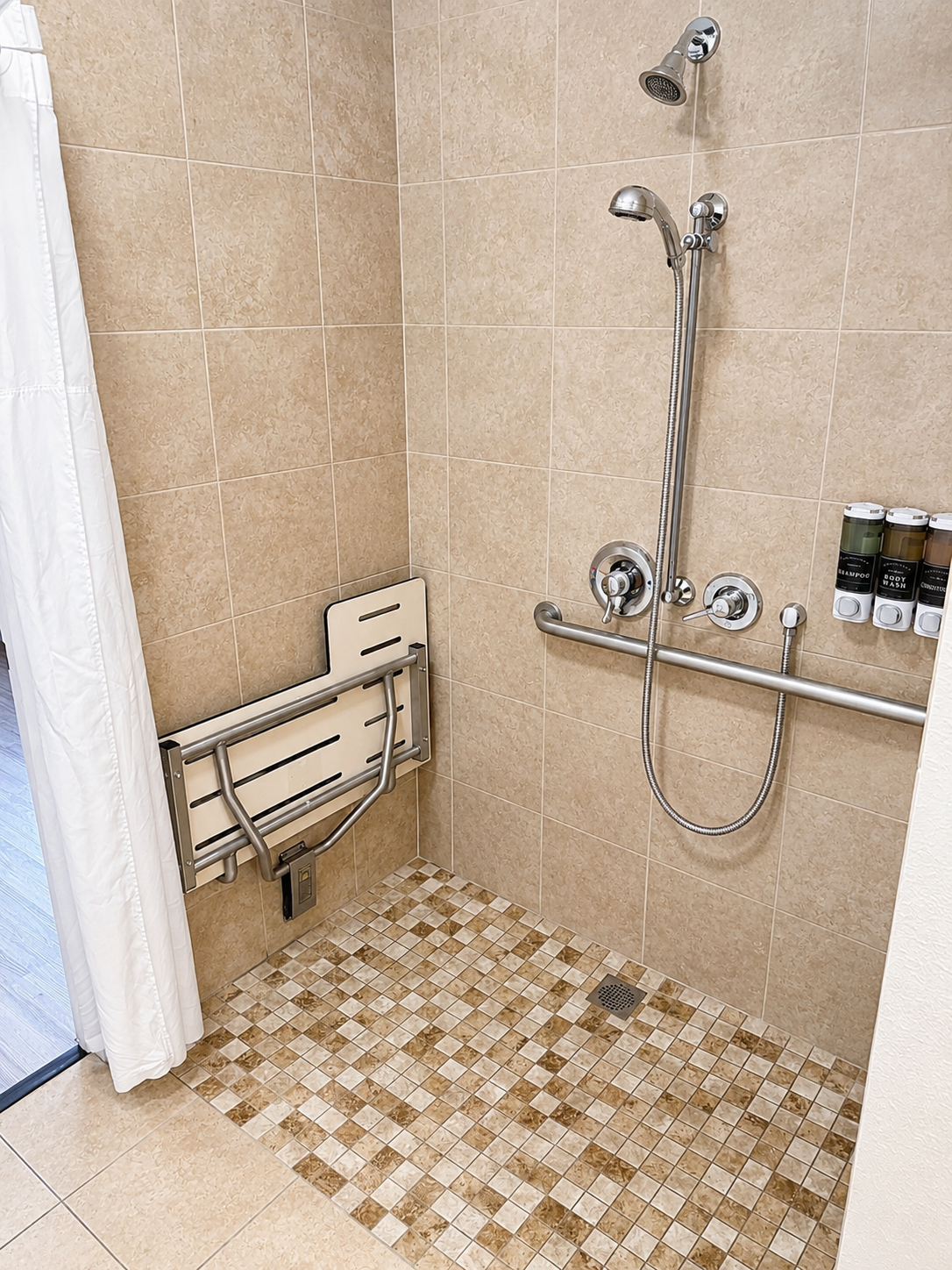 Walk-in shower with grab bars, a fold-down seat, and handheld showerhead